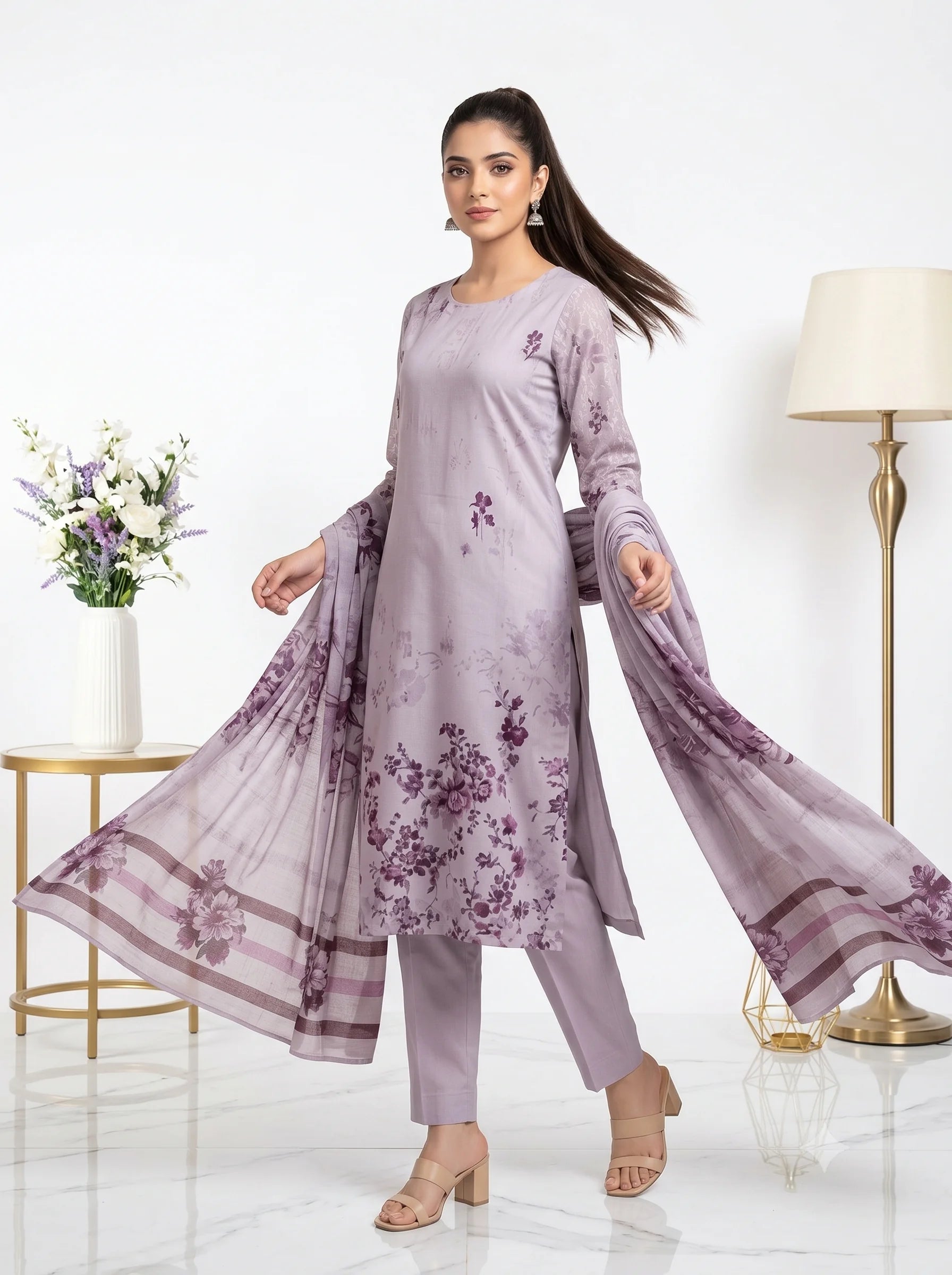 Woman wearing a light purple outfit with floral patterns in a well-lit room.