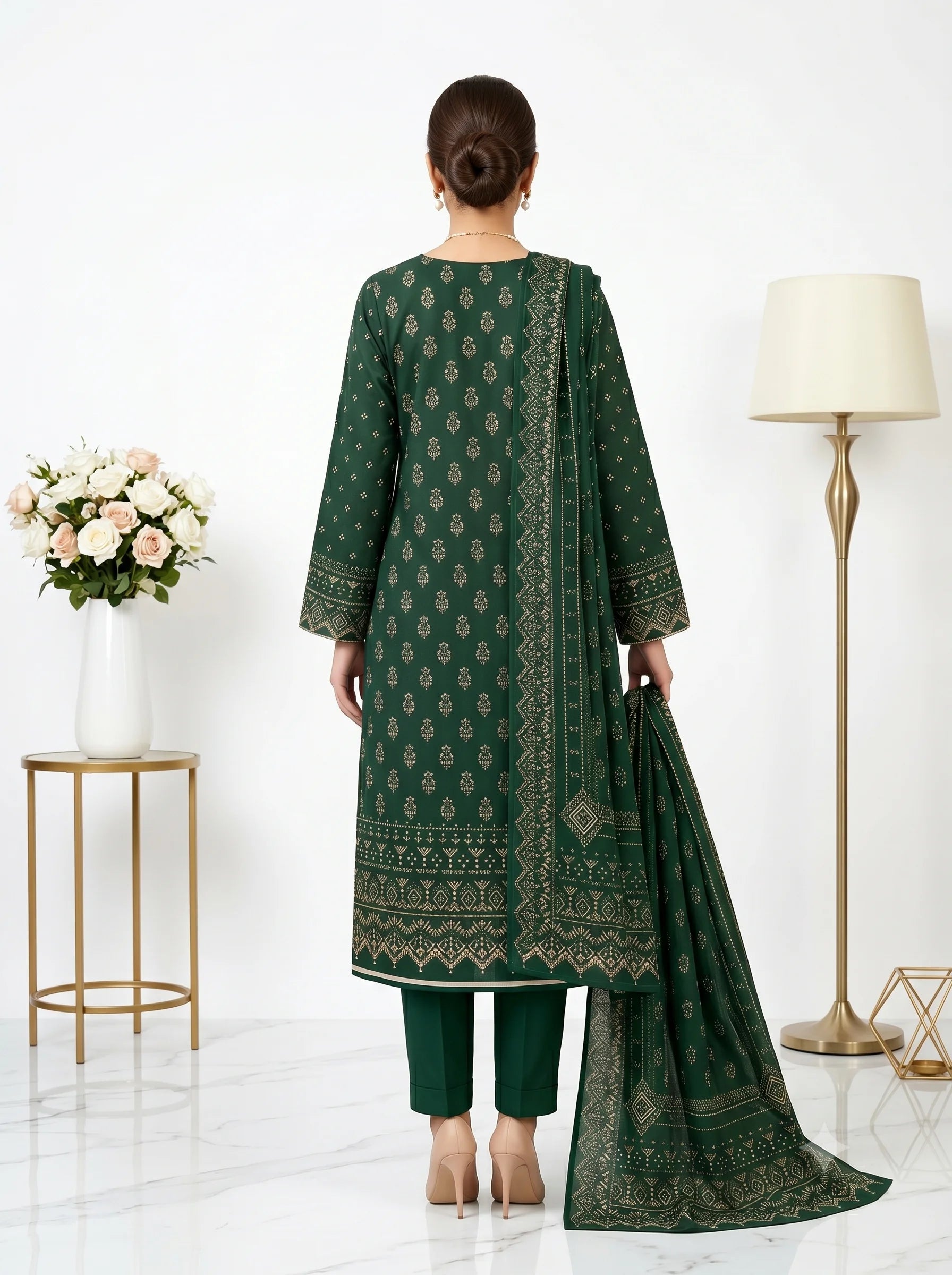 Woman wearing a green embroidered outfit with a matching dupatta in a minimalistic room.