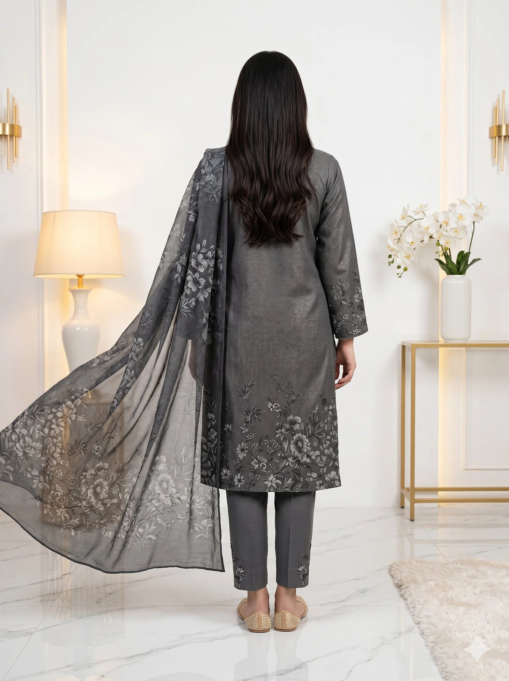 Woman wearing a gray embroidered outfit with a flowing dupatta in a well-lit room.