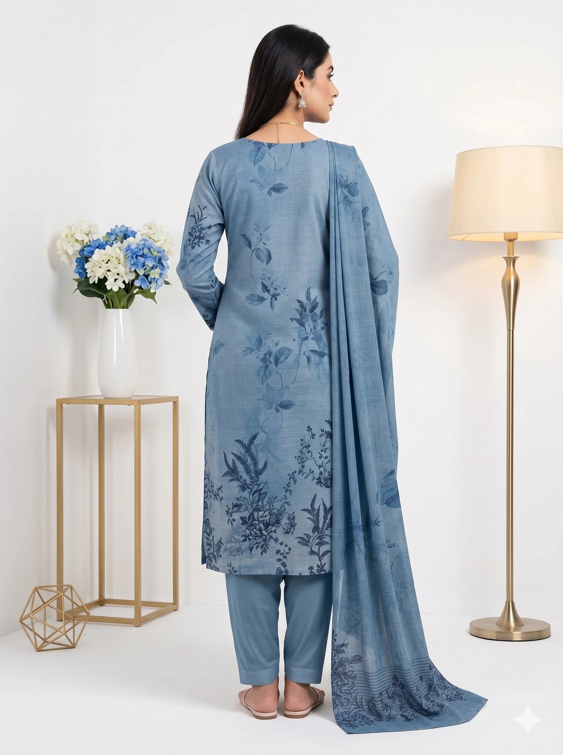 Woman wearing a blue floral kurta with matching pants in a minimalistic setting.