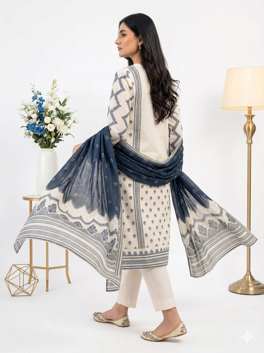Woman wearing a white and blue embroidered outfit with a matching dupatta in a well-lit room.