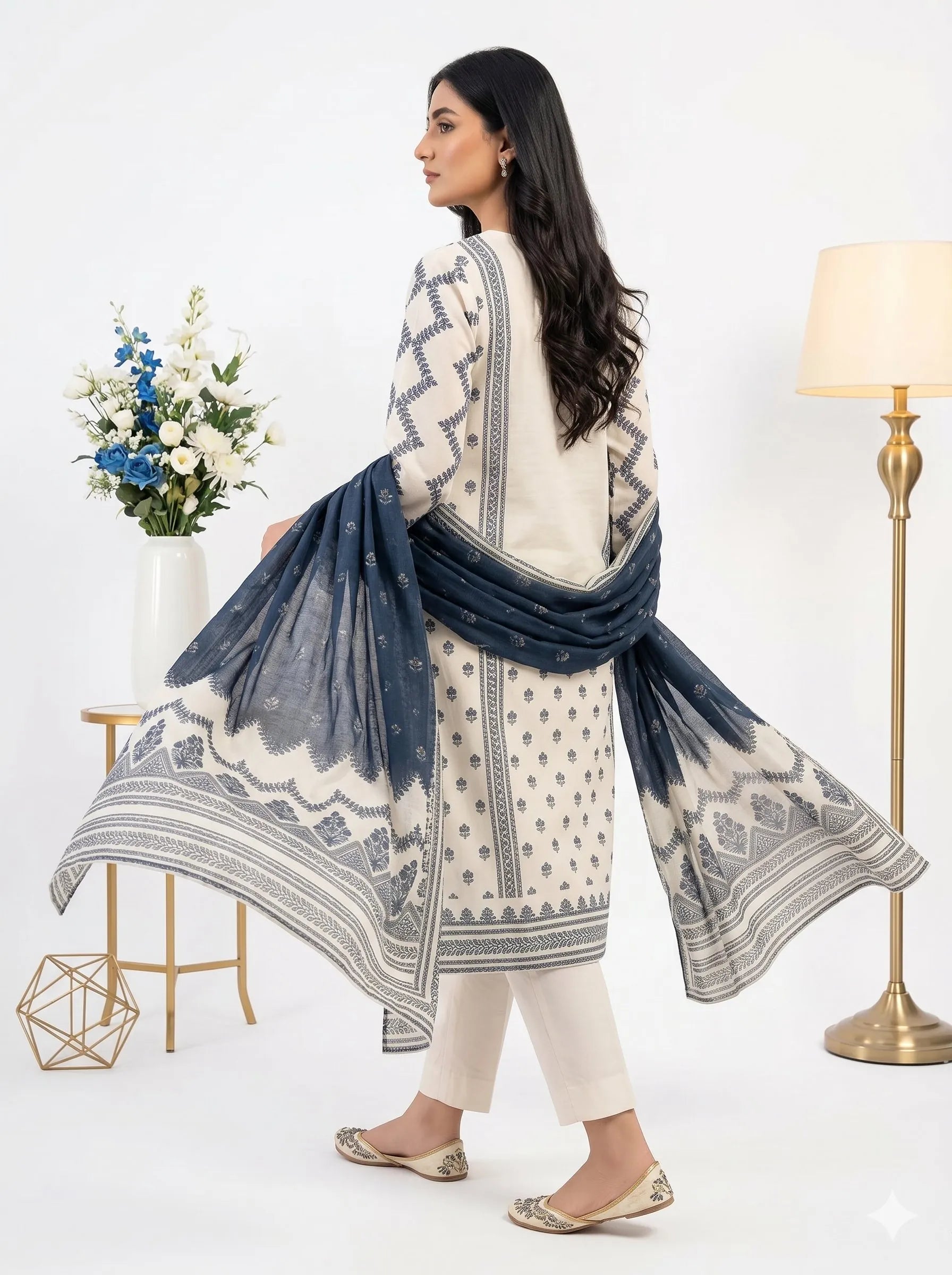 Woman wearing a white and blue patterned dress with a matching shawl, standing against a white background.