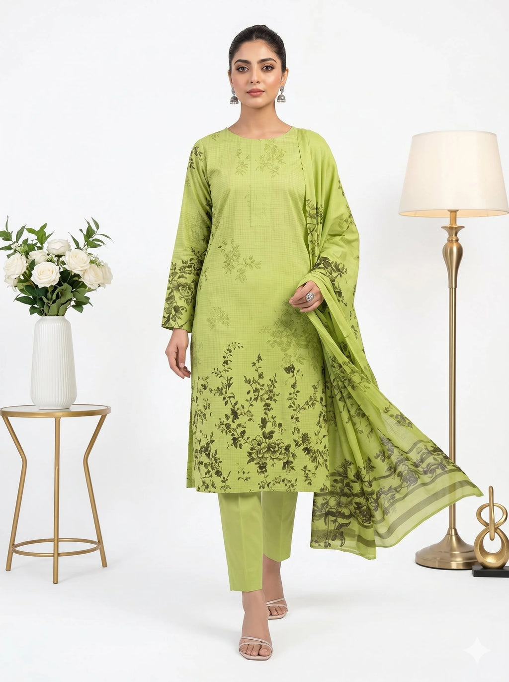 Woman wearing a green traditional outfit with a floral pattern in a minimalistic setting.